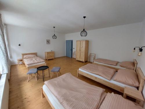 HolanyChalupa U Studánky的一间卧室配有三张床和一张桌子及椅子