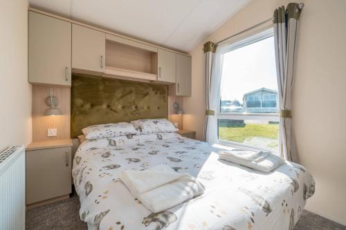 Longniddry3 Bed Static Caravan-Seton Sands的一间卧室设有一张床和一个大窗户