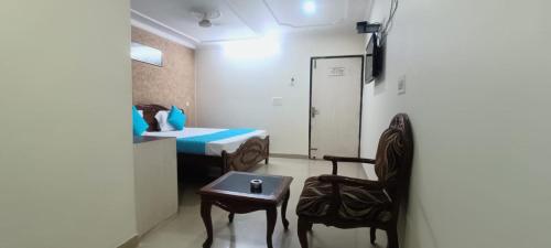 阿格拉Hotel Jigyasa By Mayda Hospitality Pvt. Ltd.的配有床、桌子和椅子的房间