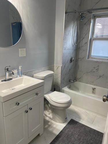 波士顿Boston Luxury Condo Style Rooms的白色的浴室设有水槽、卫生间和浴缸。