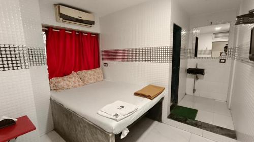 孟买Hotel Janata的小房间,配有床和红色窗帘