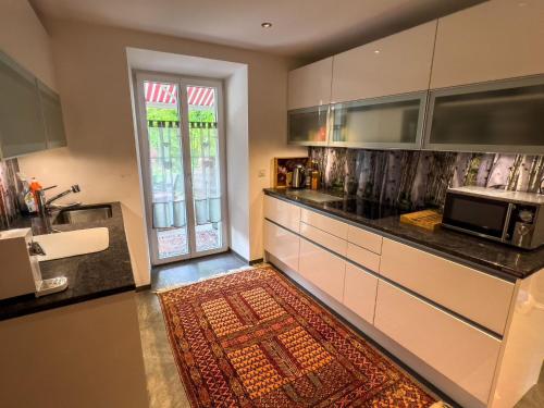 瓦尔腾斯堡Ferienwohnung Waltensburg的厨房配有白色橱柜和厨房地毯。