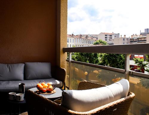 马赛Charment appartement à Marseille - Prado A/C的阳台配有沙发和带一碗水果的桌子。