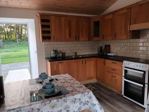 韦克斯福德Ivy Cottage的厨房配有木制橱柜和一张带餐具的桌子。