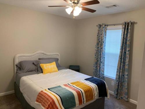奥古斯塔Comfy, Stylish Townhome Near I-20!的一间卧室配有一张带吊扇和窗户的床。
