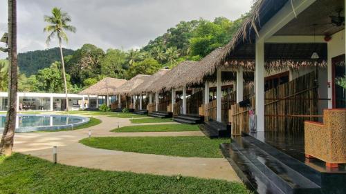 爱妮岛Bebeladan Beach Resort, In The Last Indigenous Corner的连排带游泳池和树木的度假建筑