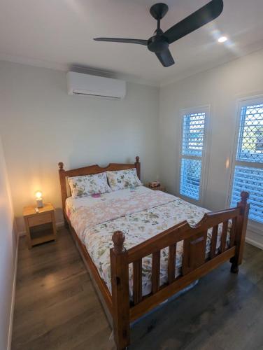 布里斯班Immaculate 2-Beds Entire House Chermside Brisbane的一间卧室配有一张木床和吊扇
