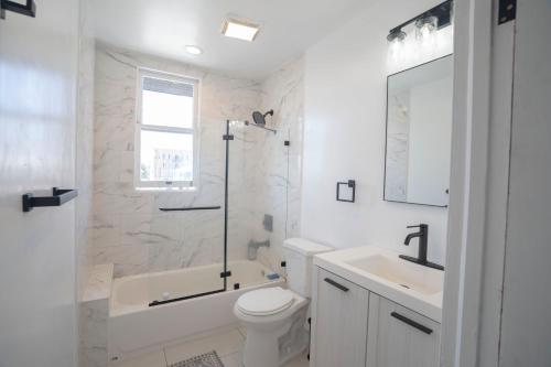洛杉矶Burlington Hostel的白色的浴室设有浴缸、卫生间和水槽。