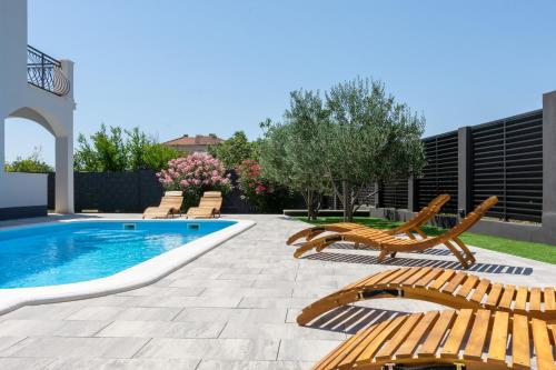 卡什泰拉Villa Kalani的一个带椅子的庭院和一个游泳池