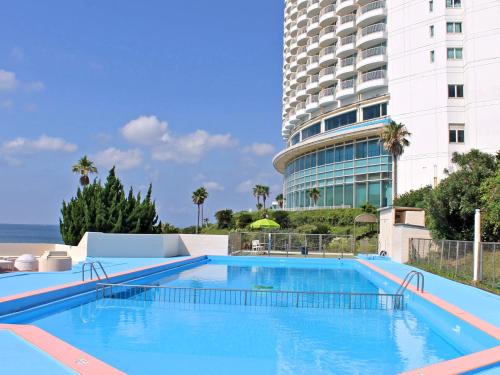 田原市伊良湖度假&会议酒店的一座高楼旁边的大型游泳池