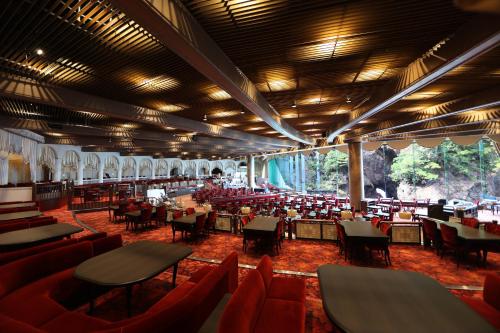 热海新赤尾酒店(Hotel New Akao)的大楼内一家餐厅,配有红色的桌椅