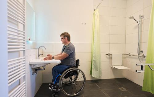 WeberstedtWaldResort的坐在浴室水槽的轮椅使用者