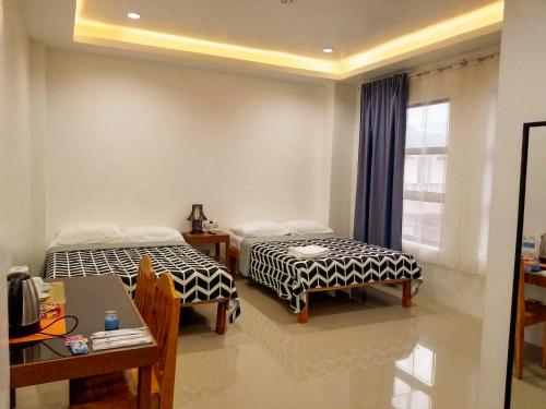GuinobatanMajestique Hotel Albay Bicol的客房设有两张床、一张桌子和一扇窗户。