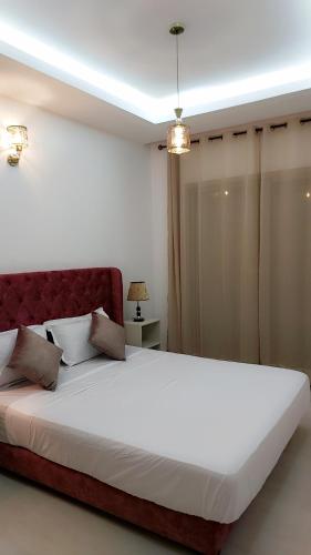 布兹尼盖Appartement Nova - Costa Bouznika的一间卧室配有一张白色大床和红色床头板