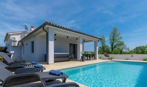 ManjadvorciVilla VINE - new luxury holiday house in a green oasis的一座房子旁带躺椅的游泳池
