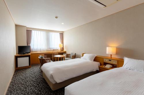 久留米市Suikouen Hotel的酒店客房设有两张床和电视。