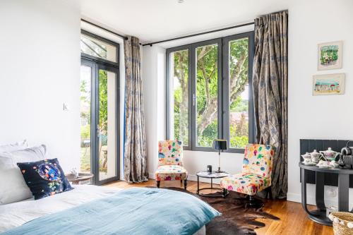 VétheuilLa Villa Lauvray的一间卧室配有一张床、两把椅子和窗户