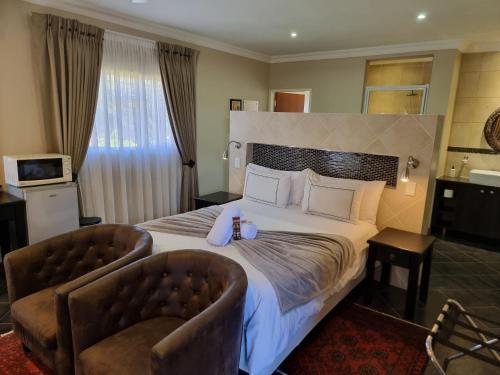比勒陀利亚格伦马里昂旅馆的酒店客房,配有一张大床和两把椅子