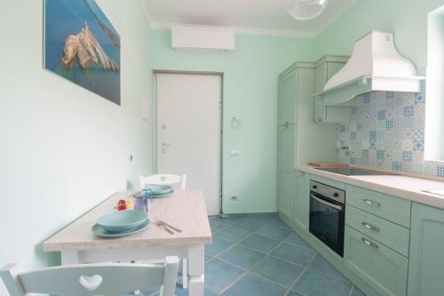 费拉约港Appartamento Sogno Marino的厨房配有白色橱柜和桌椅