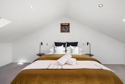 皇后镇Beautifully styled central home的白色卧室配有一张带白色枕头的大床