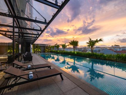 岘港Bay Capital Danang的一座享有日落美景的建筑屋顶上的游泳池