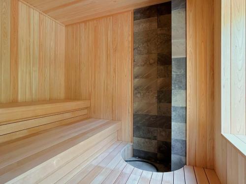 JozankeiSuigan的一间铺有木地板并配有石墙的桑拿浴室