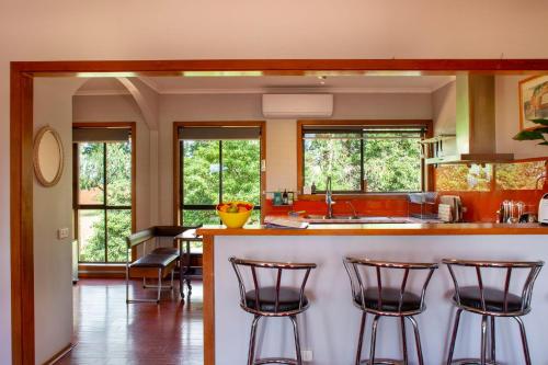 SilvanTreetops - Yarra Valley Country Apartment的厨房配有三把吧台凳和台面
