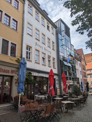 耶拿Ferienwohnungen am Jenaer Markt, Mitten im Zentrum, für bis zu 5 und 6 Personen的一组桌子和伞在建筑前