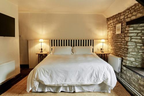 诺斯利奇The Sherborne Arms的一间卧室配有一张带两盏灯的大型白色床。