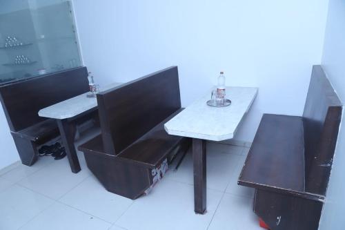 JālgaonHotel Kewal INN的一张桌子、两把椅子和一张桌子,上面有一瓶