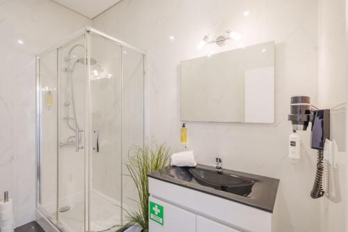 波尔图Feel Porto Historical Apartments的一间带玻璃淋浴和水槽的浴室