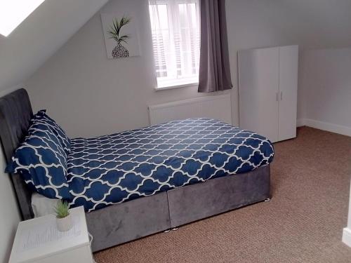Cosy & Spacious 4 Bedroom House with Free Parking in Birmingham的一间卧室配有一张带蓝色棉被的床和窗户。