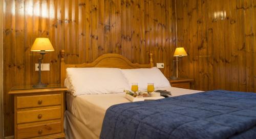 兰索尔奥纳多拉达埃尔塔特公寓酒店的一间卧室配有一张带两盏灯和两杯饮料的床。
