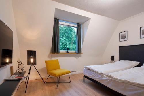 鲁尔河畔米尔海姆Renoviertes Design Apartment mit Toller Terasse的一间卧室配有一张床和一张黄色椅子