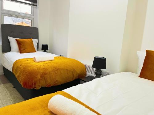 莱斯特Opal Apartment的一间卧室配有两张带黄白色床单的床
