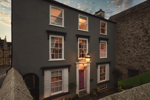塔维斯托克One Drake Road, Tavistock, Devon的一间黑房子,设有白色的窗户和红色的门