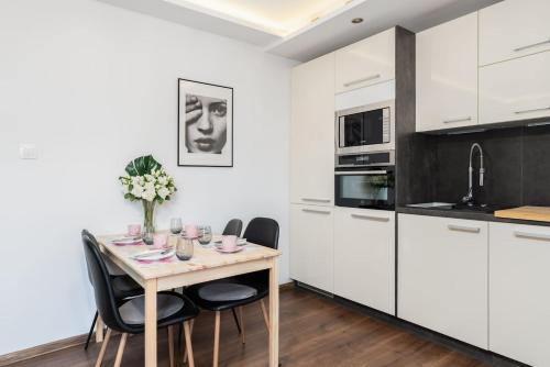 波兹南Kosińkiego Apartament Poznań by Renters的厨房配有白色橱柜和一张带椅子的木桌