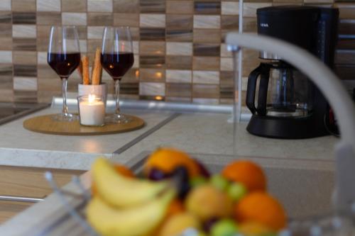 马塔拉Maistro Suites with pool, Matala的厨房柜台上的两杯葡萄酒和水果