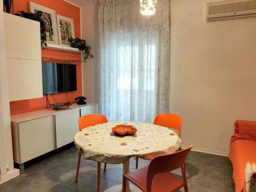 龙基德伊莱焦纳里Tre Continenti - Appartamento con parcheggio privato的一间带桌子和橙色椅子的用餐室