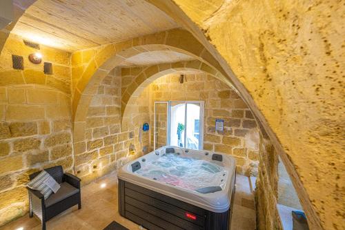 KerċemTal-Andar Farmhouse的一间石墙内大浴室,配有浴缸
