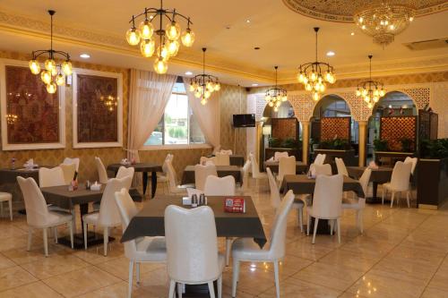 沙迦沙迦国际机场酒店的用餐室配有桌椅和吊灯。