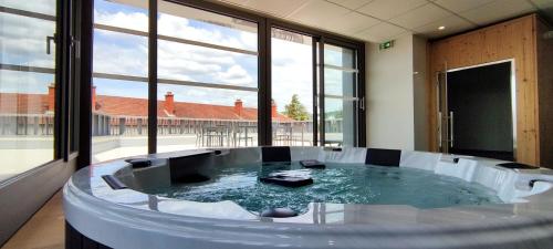 隆勒索涅Logis Hotel du Parc-Restaurant - Le Rouget de Lisle的带大窗户的客房内的热水浴池