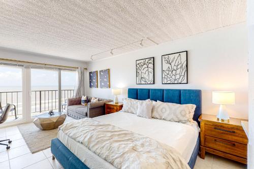 加尔维斯敦Ocean Escape By the Sea的一间卧室配有一张大床和蓝色床头板
