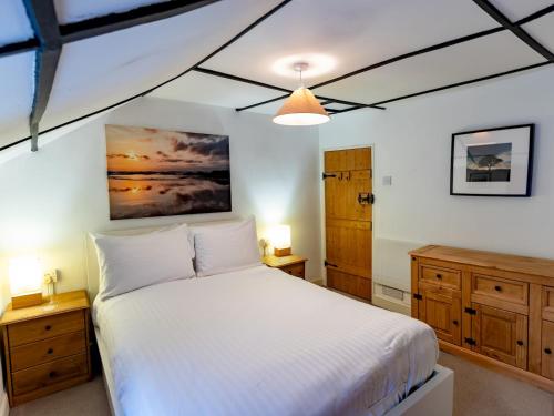 布里奇沃特Pass the Keys Cosy Cottage with Fireplace的卧室配有白色的床和木制橱柜。