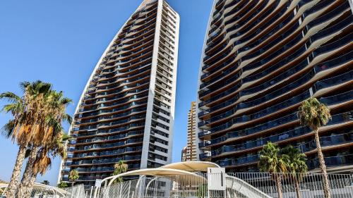 贝尼多姆SUNSET WAVES sea view apartments的两座高大的建筑,前面有棕榈树