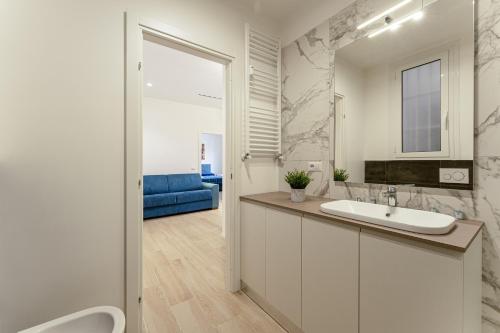 罗马Piazza Pio Suite Home的白色的浴室设有水槽和蓝色的沙发。