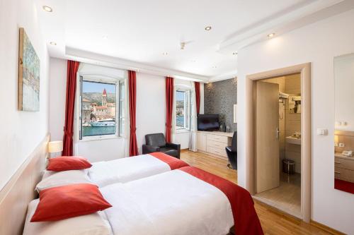 特罗吉尔Heritage Hotel Vila Sikaa的酒店客房配有一张带红色枕头的大床
