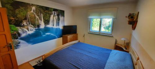 阿尔杰什河畔库尔泰亚Casă de vacanţă ,,La Vălucu"的卧室配有一张蓝色的床,墙上挂着一幅画