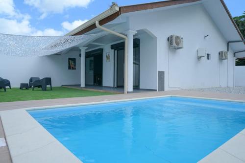 MatouryLa Palmeraie Lodge Terrasse & Piscine et Jacuzzi的白色房子前的游泳池