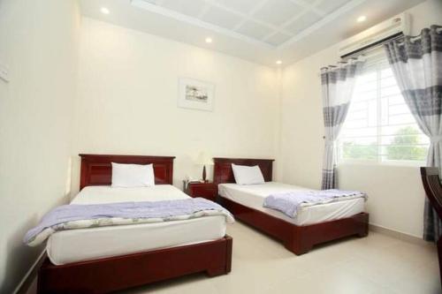 多森Nha Khach Hai Quan的一间卧室设有两张床和窗户。